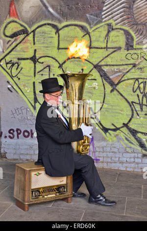 Street performer seduta sul vecchio radiogramma riproduzione di Tuba con fiamma uscente in London Regno Unito Foto Stock
