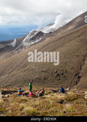 Walkers fermarsi a guardare il vapore ascendente dal vulcanico attivo sui fianchi del monte Tongariro nel Parco Nazionale di Tongariro in Nuova Zelanda Foto Stock