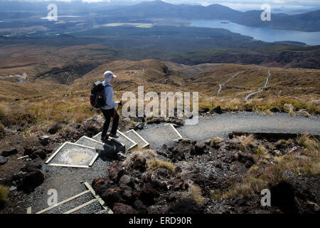 Una femmina di un escursionista in un bianco cappello per il sole sulla ripida discesa di avvolgimento di th Tongariro Alpine Crossing in Nuova Zelanda Foto Stock