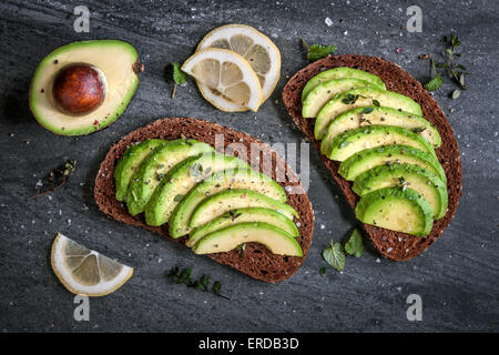 Sandwich di Avocado on dark pane di segale fatto con fresco affettato avocadi dal di sopra Foto Stock