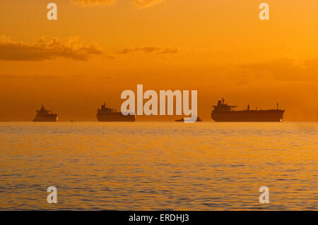 Le navi in attesa al di ancoraggio nel Golfo del Messico presso sunrise, prima di entrare in Galveston Bay sul loro modo al Porto di Houston, Texas, Stati Uniti d'America Foto Stock