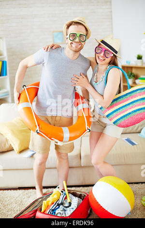 Felice ragazza e il suo fidanzato in occhiali e cappelli ottenere pronto per il viaggio Foto Stock