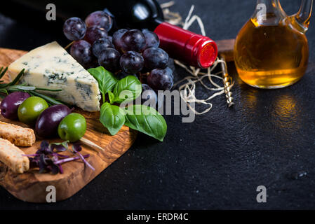 Scheda di tapas con formaggio, olive, uva e vino rosso,cibo sullo sfondo di confine Foto Stock