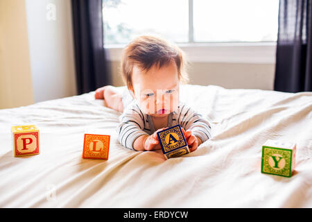 Caucasian bambina giocando con i blocchi sul letto Foto Stock