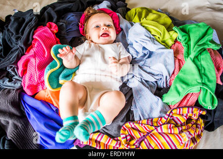 Caucasian Baby girl recante nella pila di servizio lavanderia Foto Stock