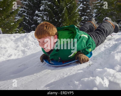 Ragazzo caucasico slittino sulla neve hill Foto Stock