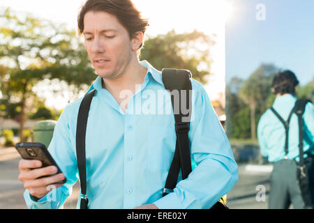 Imprenditore ispanica sms sul cellulare all'aperto Foto Stock