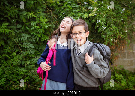 Razza mista del fratello e sorella di ridere in uniformi di scuola Foto Stock
