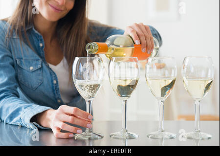 La donna caucasica versando bicchieri di vino bianco Foto Stock