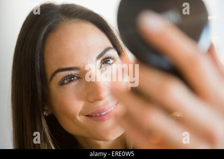 La donna caucasica ammirando se stessa in specchio compatto Foto Stock