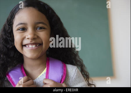 Sorridente razza mista studente indossando uno zaino in aula Foto Stock
