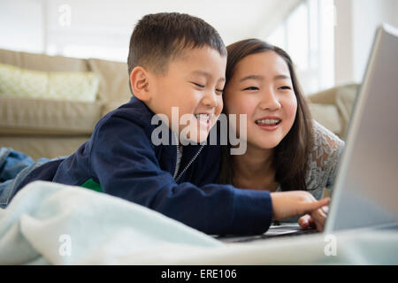 Asian fratello e sorella utilizzando laptop sul soggiorno piano Foto Stock