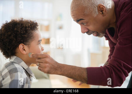 Razza mista nonno tirando magic moneta da orecchio del nipote Foto Stock