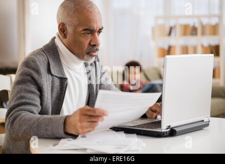 Razza mista uomo il pagamento di fatture su laptop Foto Stock