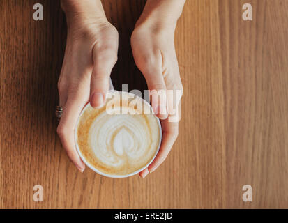 Mani tazza di caffè con foglie prelevate nel latte Foto Stock