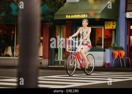 I vecchi donna caucasica Bicicletta Equitazione in crosswalk Foto Stock