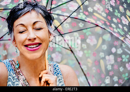 I vecchi donna caucasica con gli occhi chiusi tenendo ombrello Foto Stock