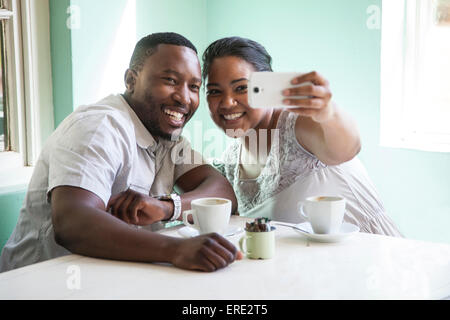 Coppia sorridente tenendo cellulare selfie a tavola Foto Stock