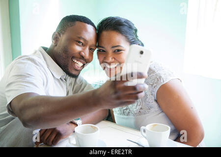 Coppia sorridente tenendo cellulare selfie Foto Stock