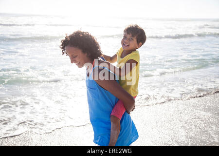 Razza mista madre figlia portante piggyback sulla spiaggia