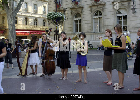 Un gruppo di giovani femmine musicisti e cantanti la pubblicità dei loro show in Avignon's Town Hall Square, nel sud della Francia, durante l'anno per un periodo di due settimane performing arts festival. Foto Stock