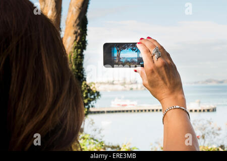 Donna ispanica tenendo cellulare fotografia della spiaggia Foto Stock