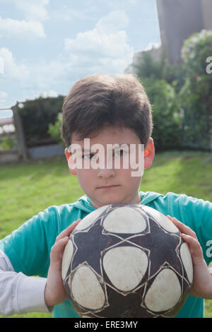 Ragazzo ispanico tenendo palla calcio in cortile Foto Stock