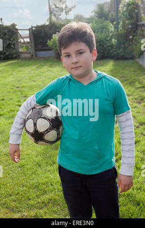 Ragazzo ispanico tenendo palla calcio in cortile Foto Stock