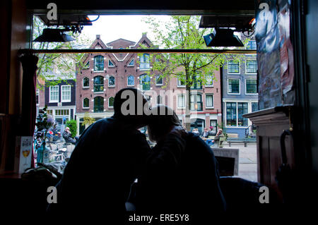 Giovane seduto all'interno di bar di Amsterdam con vista al di fuori Foto Stock