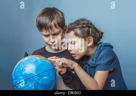 Ragazzo adolescente con una ragazza guardando un mappamondo che mostra i pollici su Foto Stock