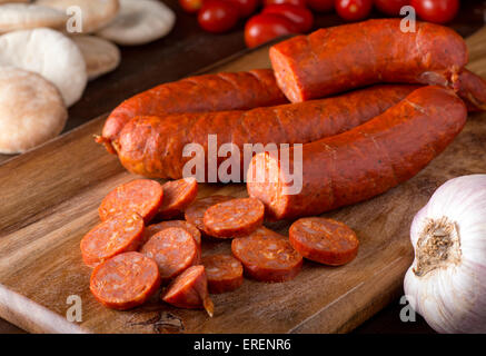 Deliziosa merguez salsicce su un tavolo rustico con pita, aglio e pomodori. Foto Stock