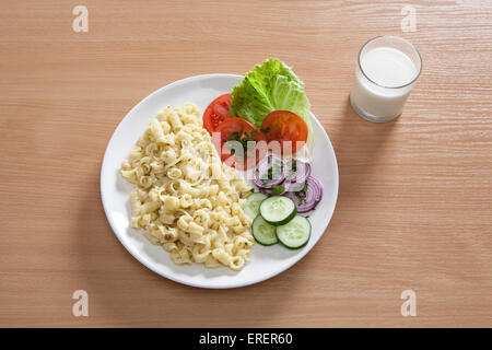 Una piastra con un semplice piatto di pasta, veg sul lato e un bicchiere di latte Foto Stock