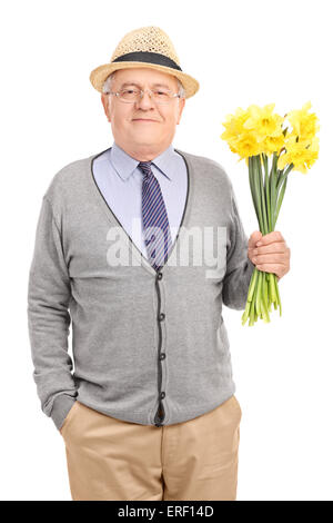 Colpo verticale di un romantico senior gentleman tenendo un mazzo di tulipani gialli e guardando la telecamera Foto Stock