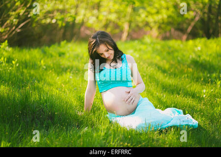 Giovane donna felice in attesa del bambino. Mani femminili holding pancia in gravidanza. Madre bella per godersi la natura. Donna incinta Foto Stock