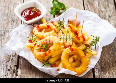 Patate fritte con calamari e rosmarino su carta bianca Foto Stock