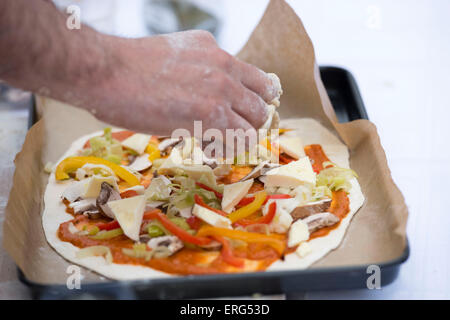 Pizza vegetariana essendo realizzati in un vassoio da forno. Foto Stock