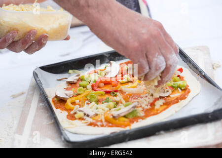 Pizza vegetariana essendo realizzati in un vassoio da forno. Foto Stock