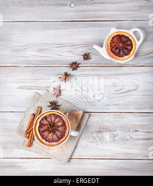 Tè marocchino con spezie e fetta di arancione sul bianco sullo sfondo di legno Foto Stock