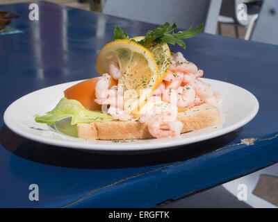 A viso aperto sandwich di gamberi con maionese, limone e più su un tavolo blu top, pesce all'aperto estate delicatezza in Oslo Norvegia Foto Stock