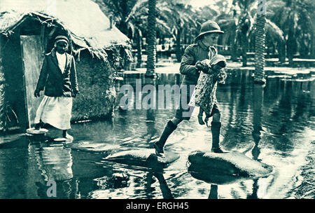 Esercito britannico in Mesopotamia durante la guerra mondiale 1: soldato che porta una ragazza in tutta l'acqua di allagamento, 1916. Il giorno moderno Iraq. Foto Stock