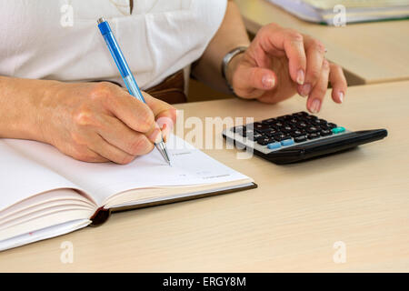 Business donna digitando su calcolatrice in ufficio Foto Stock