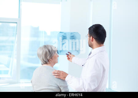 Medico maschio mostra x-ray per il suo paziente in ospedale Foto Stock