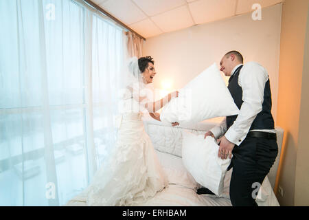 Cuscino lotta della sposa e lo sposo in una camera di hotel Foto Stock