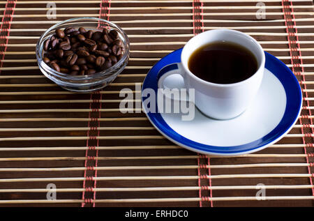 Tazza di caffè con caffè in chicchi su un piattino Foto Stock