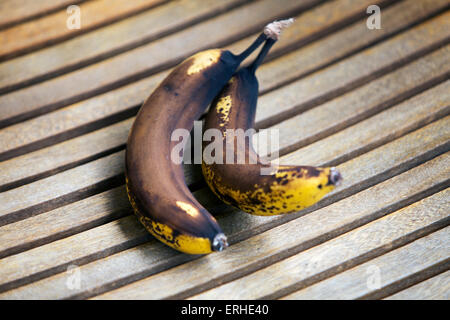 Due banane stramature su legno Foto Stock