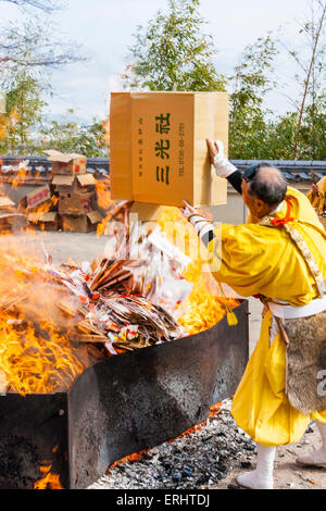 Giappone, Nishinomiya, Mondo Yakujin tempio. Masterizzazione annuale rituale, con giallo derubato yamabushi monaci, Shugendo, gettando scatole di vecchie omikuji nel fuoco. Foto Stock