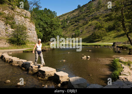 Regno Unito, Inghilterra, Derbyshire, Dovedale, Fiume Colomba, visitatore utilizzando stepping stone crossing in estate Foto Stock