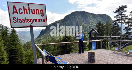 Mittenwald, Germania. 03 Giugno, 2015. Un funzionario di polizia su una piattaforma di osservazione al Ederkanzel mountain hotel controlla la zona di confine austro-tedesca regione dietro un cartello con la scritta "Attenzione - frontiera nazionale' vicino a Mittenwald, Germania, 03 giugno 2015. I capi di Stato e di governo del G7 Paesi si sono riuniti per il loro incontro al vertice dal 07 al 08 giugno 2015 a Schloss Elmau vicino a Garmisch-Partenkirchen. Foto: PETER KNEFFEL/dpa/Alamy Live News Foto Stock