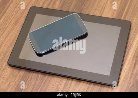 Vista dall'alto di smart phone e tablet con schermo vuoto sul tavolo di legno. Foto Stock
