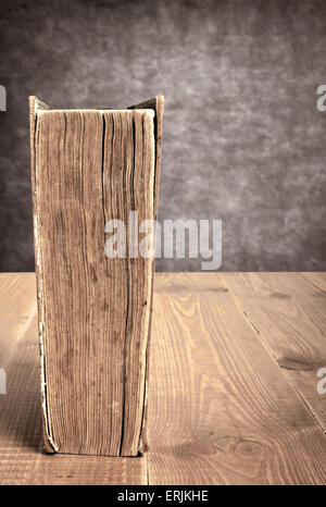 Vintage libro sul tavolo marrone fatto di assi di legno vicino alla parete di cemento Foto Stock